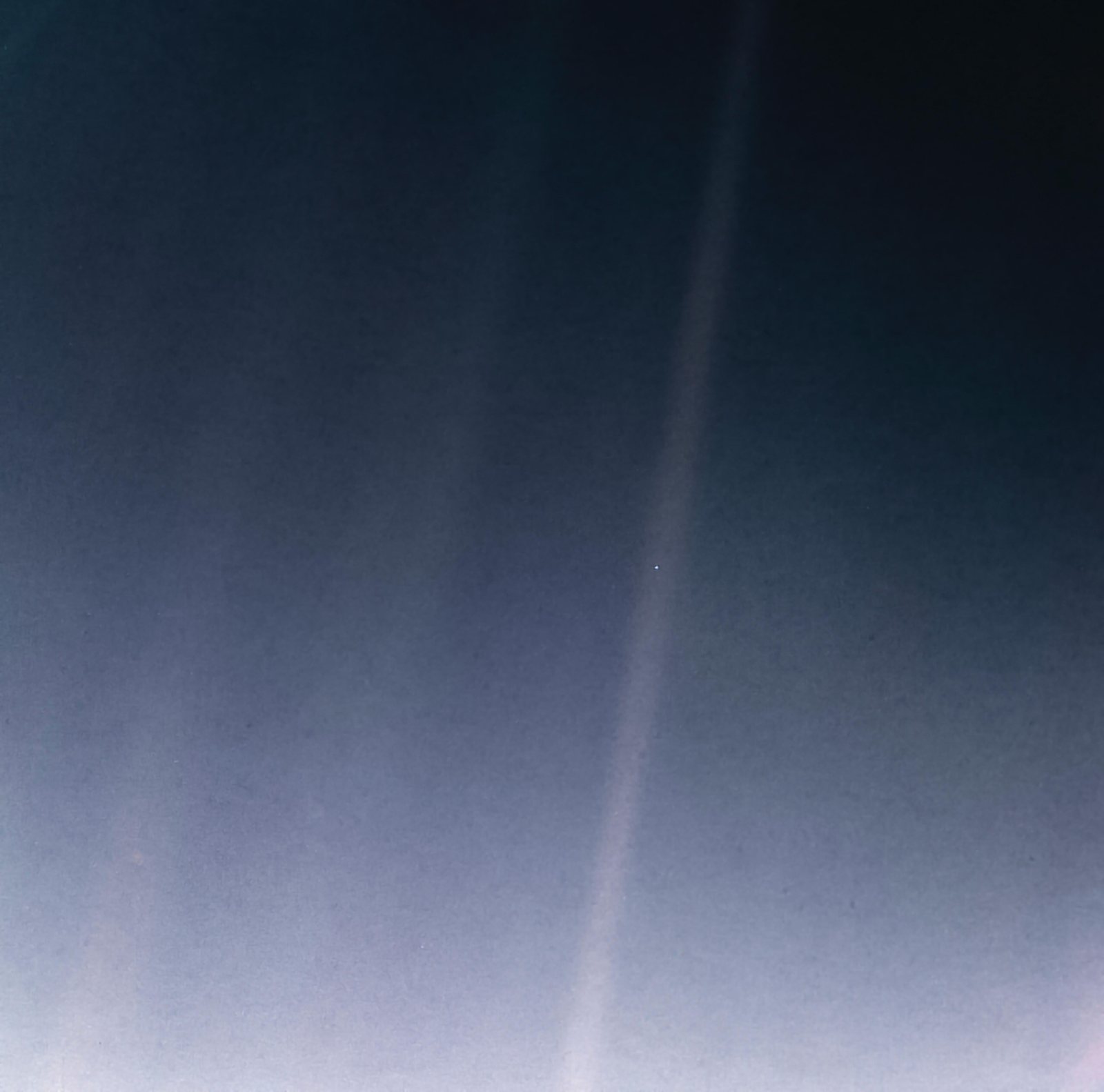 The Earth as a single pale dot inside a band of scattered sunlight, seen by Voyager 1 from about six billion kilometres away.